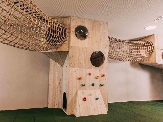 Indoor-Spielbereich mit Kletterwand und Hängebrücke aus Netz